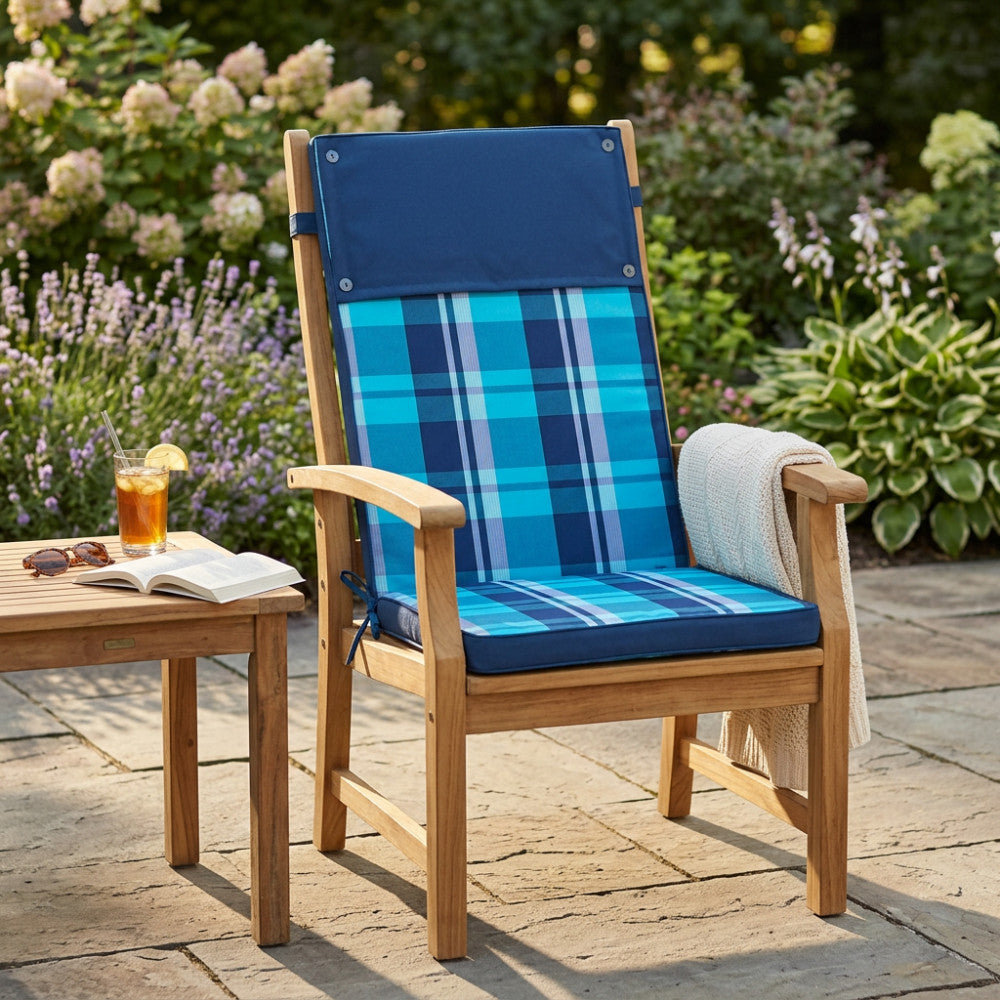 Sedia da esterno in legno con cuscino alto moderno blu e azzurro in un rigoglioso giardino estivo.