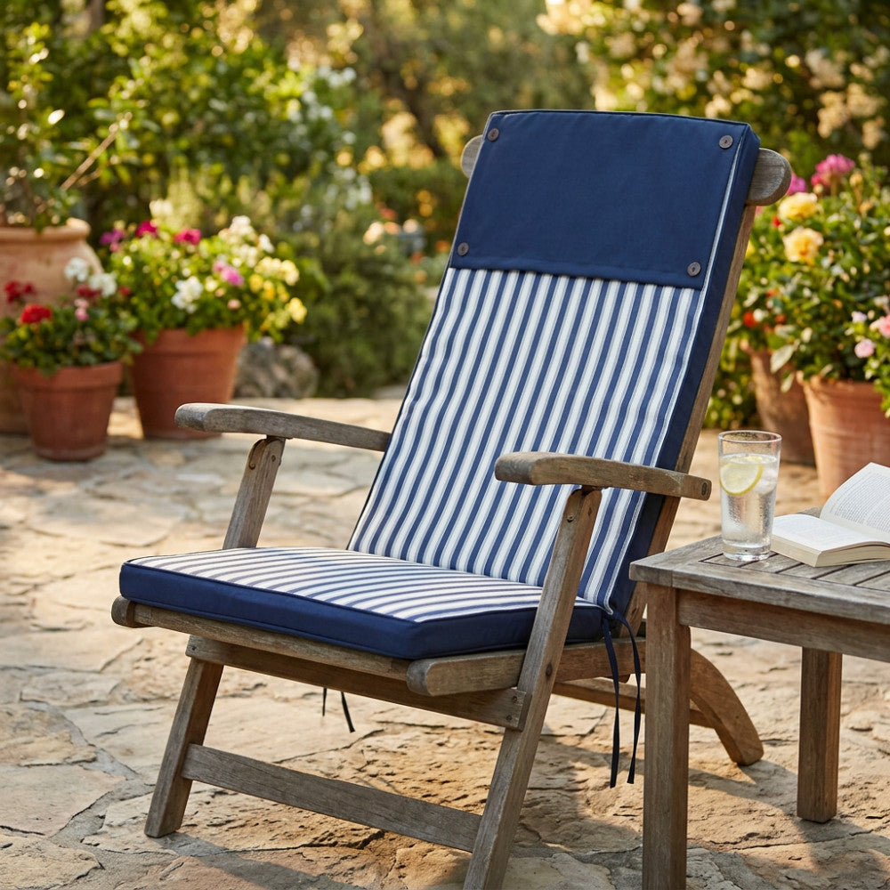 Cuscino Real Alto Riga Blu in poliestere posizionato su una sedia in legno in un giardino soleggiato.