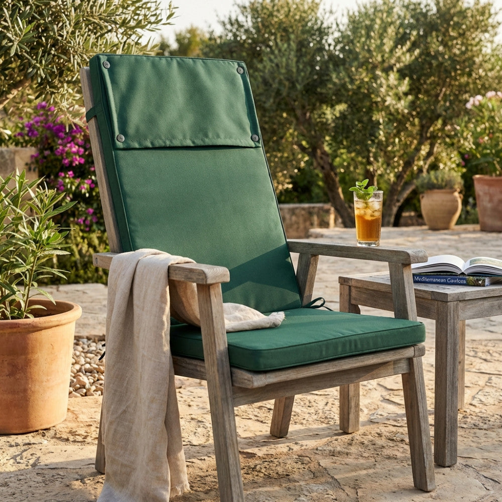 Cuscino Real Alto verde scuro posizionato su una sedia in legno da esterni, illuminato dalla luce solare in un giardino.