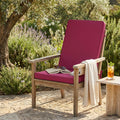 Cuscino Real Medio color magenta posizionato su una poltrona in legno in un elegante giardino.