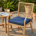 Cuscino seduta Real in poliestere blu scuro posizionato su una sedia in rattan naturale in un ambiente outdoor.
