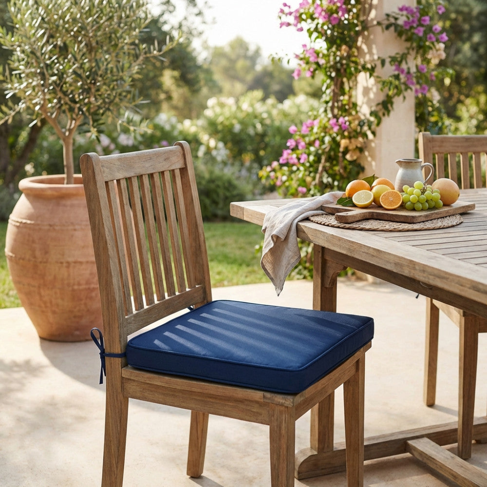 Cuscino moderno blu scuro su una sedia in legno di teak accanto a un tavolo da pranzo all'aperto.