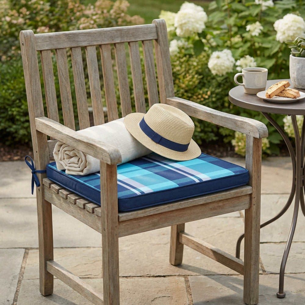 Cuscino in poliestere blu azzurro su sedia in teak, decorato con un cappello di paglia e una coperta arrotolata.