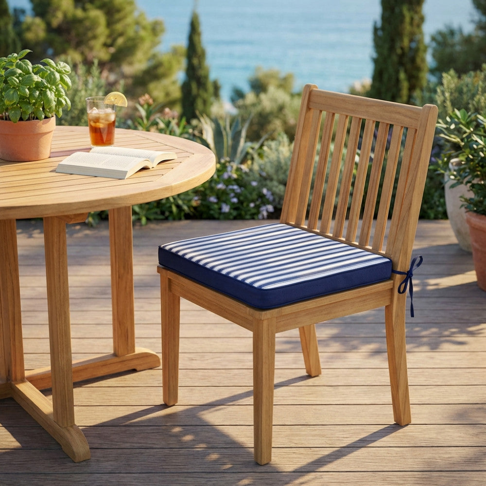 Sedia in teak con cuscino nautico a righe blu, ambientata su una terrazza con vista panoramica sul mare.