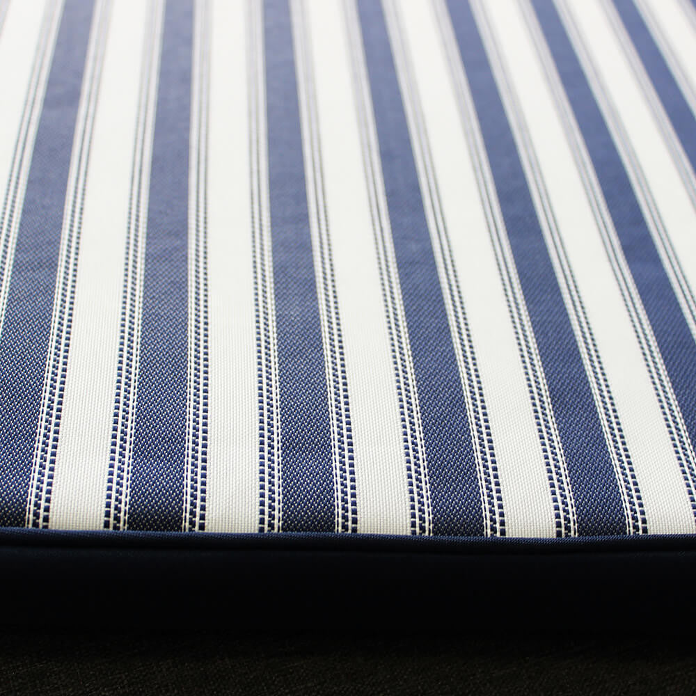 Dettaglio ravvicinato della trama in poliestere premium del cuscino a righe blu e bianche.