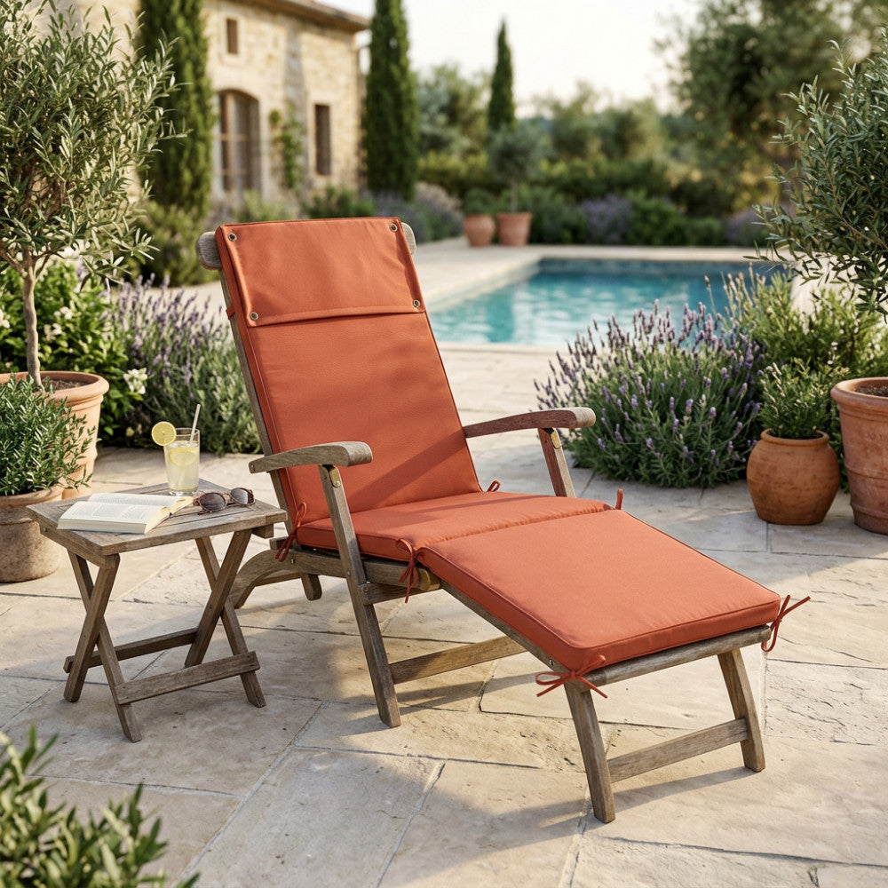 Cuscino Real Steamer arancione su una seduta in legno a bordo piscina, illuminato dalla luce naturale.