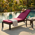 Cuscino Real Steamer Bordeaux in poliestere magenta posizionato su un lettino in legno a bordo piscina, con un cappello di paglia appoggiato.