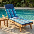 Cuscino Real Steamer a quadri blu e azzurri posizionato su un lettino in legno a bordo piscina.