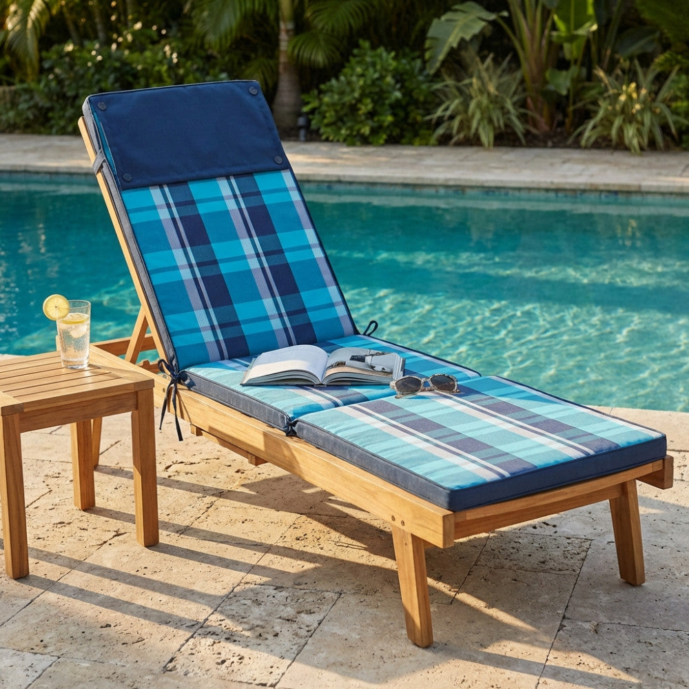 Cuscino Real Steamer a quadri blu e azzurri posizionato su un lettino in legno a bordo piscina.