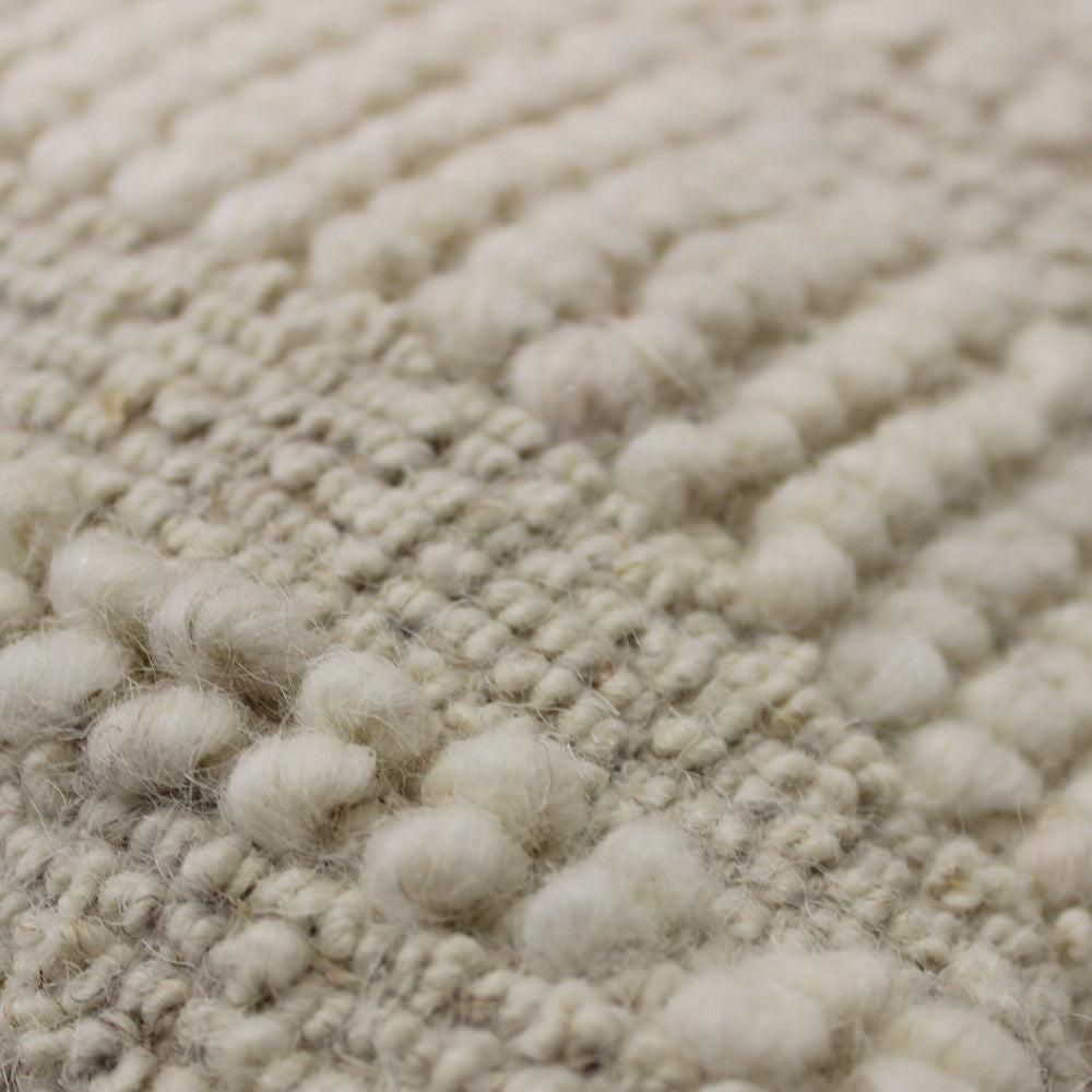 Macro fotografia della texture in pura lana, che mostra i nodi artigianali e la morbidezza del tessuto.