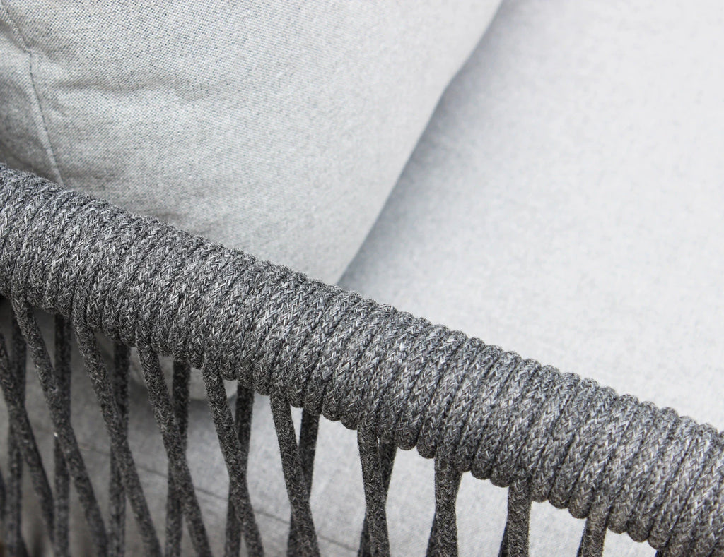 Dettaglio Intreccio del Set salotto da esterno Madeira 2P in alluminio verniciato antracite con cuscini grigi, composto da divano a due posti, due poltrone e un tavolino, ambientato in un patio con ghiaia bianca e parete in pietra