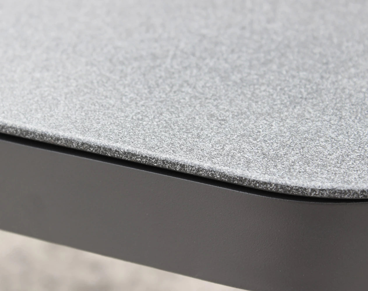 Dettaglio dei cuscini del Set salotto da esterno Madeira 2P in alluminio verniciato antracite con cuscini grigi, composto da divano a due posti, due poltrone e un tavolino, ambientato in un patio con ghiaia bianca e parete in pietra