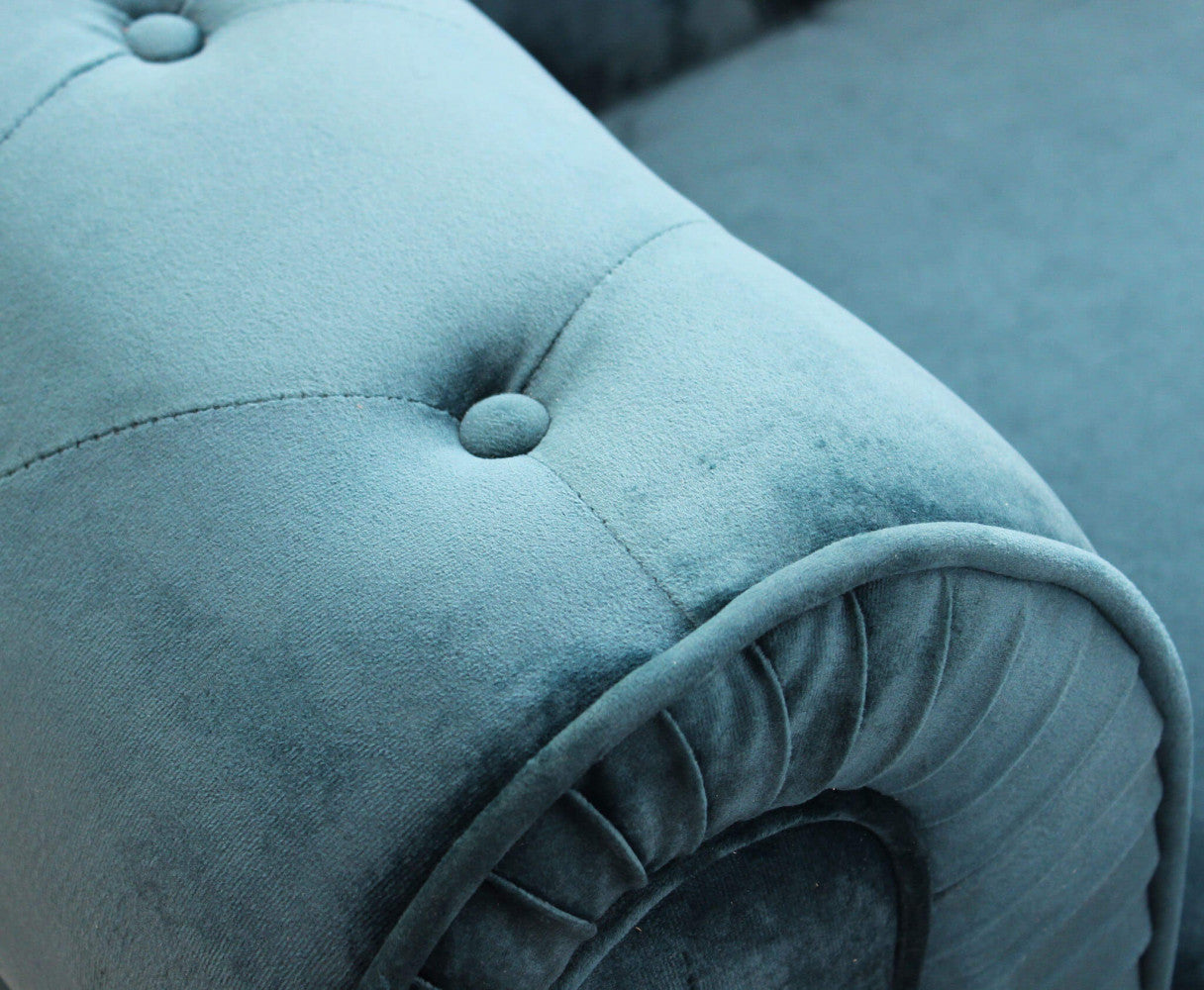 Primo piano della lavorazione capitonnè dei braccioli sul velluto blu del divano Chesterfield, che evidenzia la texture e i bottoni.