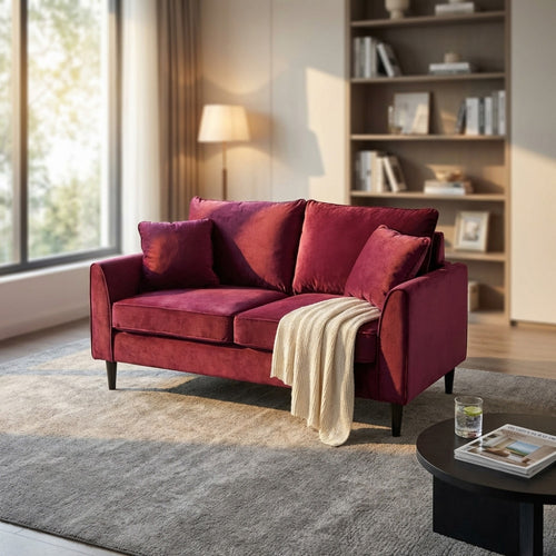 Divano in velluto rosso Chandler posizionato in una zona living moderna con libreria in legno.