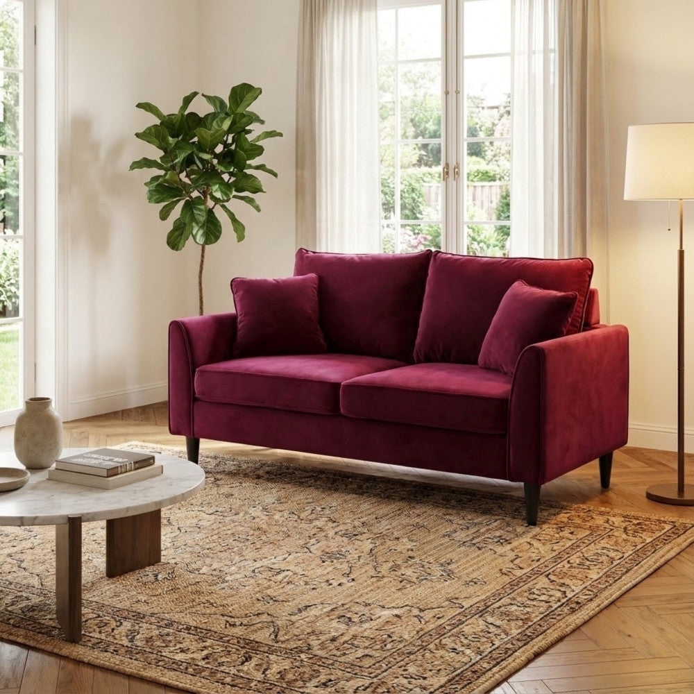 Divano Chandler in velluto rosso in un salotto dal design classico con tappeto decorato e tavolino in marmo.