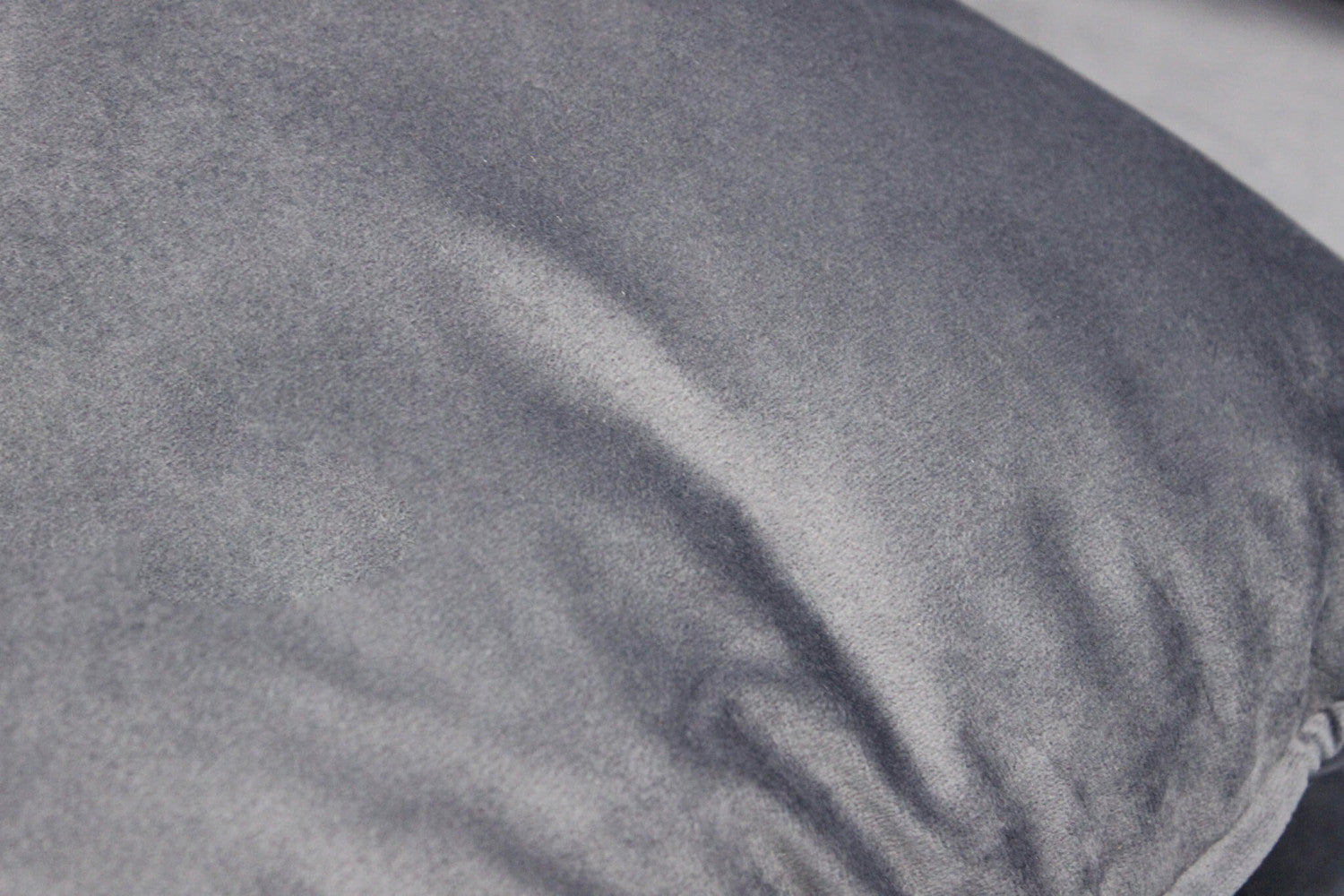 Primo piano della texture in velluto grigio chiaro del cuscino, che mostra la morbidezza del tessuto.