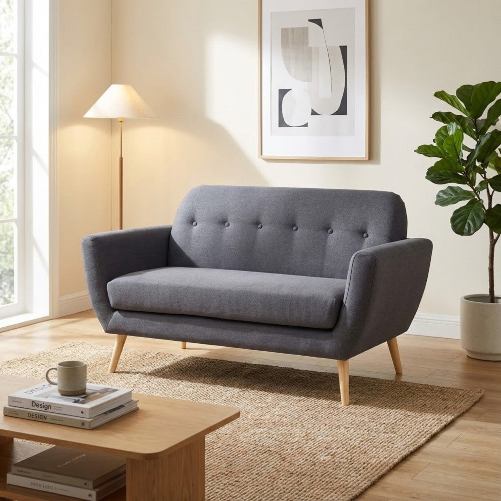 Divano Burton in tessuto grigio scuro inserito in un living dal design scandinavo, abbinato a un tappeto in fibre naturali e tavolino in legno.