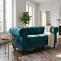 Divano 2 posti Chesterfield in velluto blu ambientato in un luminoso salotto con pianta decorativa.