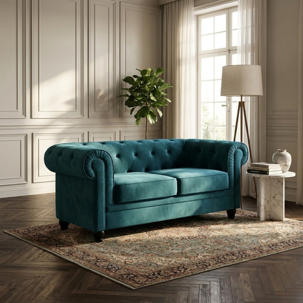 Divano in velluto blu Chesterfield inserito in un contesto di design con lampada da terra e tavolino in marmo.