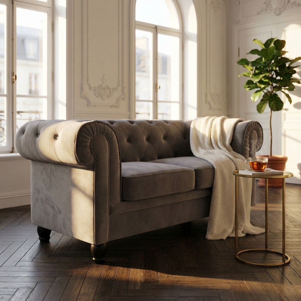 Divano 2 posti Chesterfield in velluto grigio illuminato dalla luce naturale in un salotto classico.