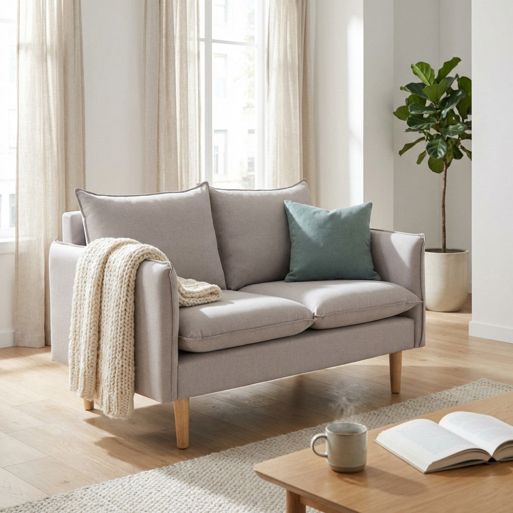 Dettaglio frontale del divano 2 posti beige con cuscini decorativi e coperta in maglia.