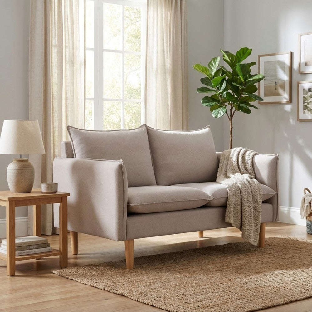 Divano beige inserito in un contesto living elegante con tappeto in iuta e pianta ornamentale.