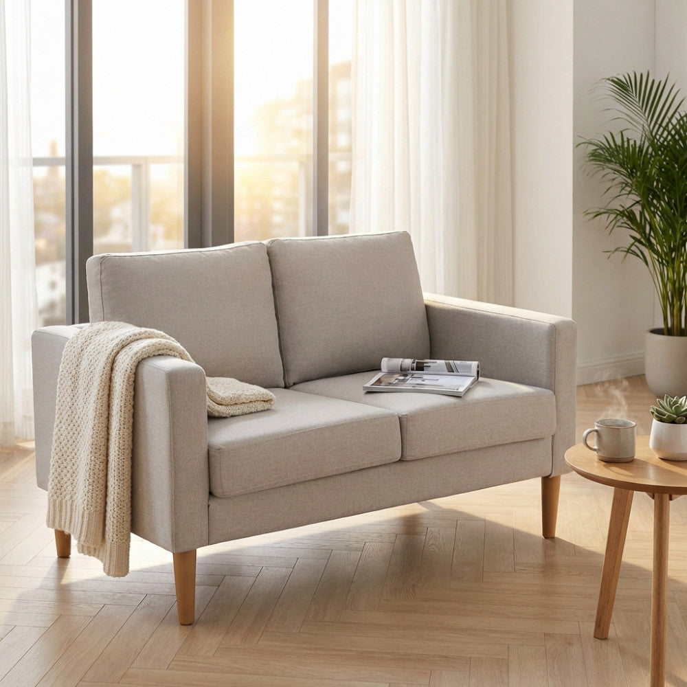 Vista frontale del divano 2 posti Ramsey beige in un soggiorno moderno con luce naturale.