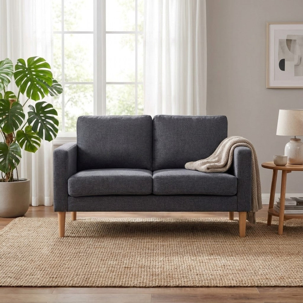 Divano Ramsey grigio scuro posizionato su un tappeto in iuta intrecciata all'interno di un soggiorno dal design scandinavo.
