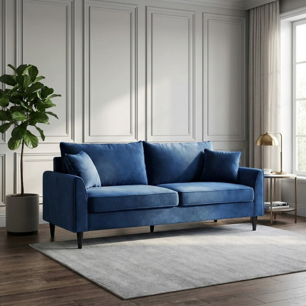 Divano a 3 posti in velluto blu posizionato in una stanza con boiserie classica e tappeto grigio chiaro.