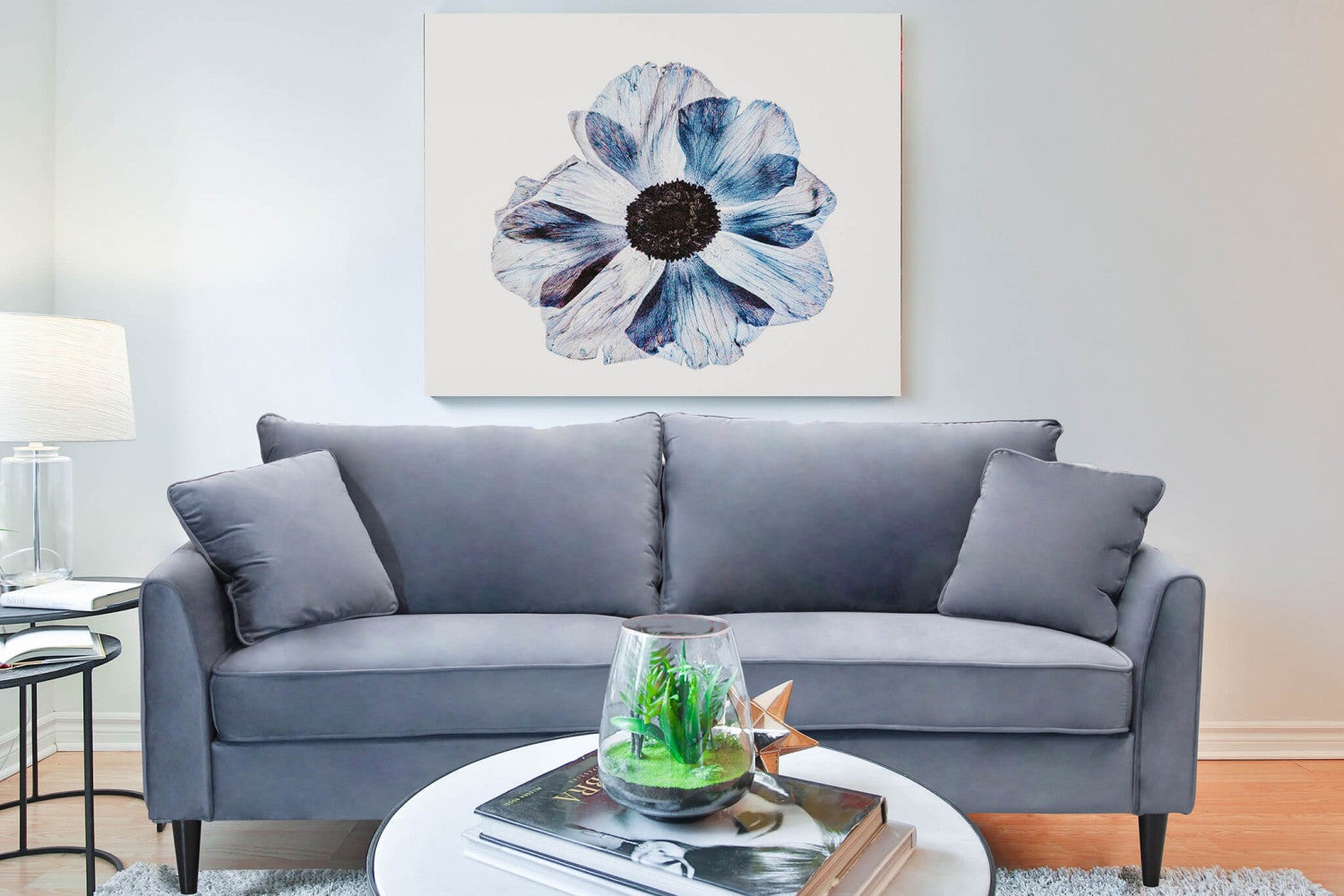 Divano Chandler in velluto grigio chiaro inserito in un salotto elegante con un grande quadro floreale a parete.