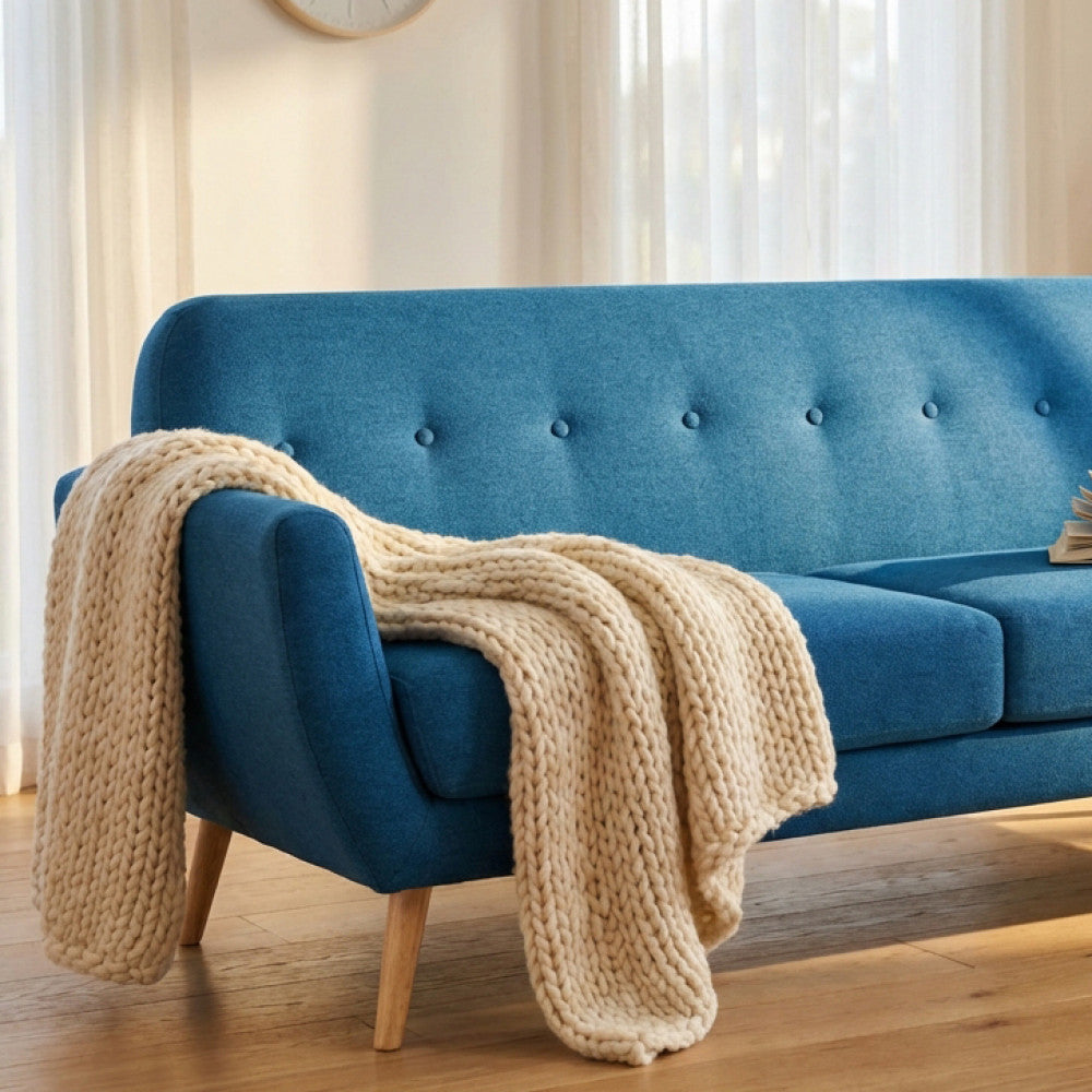 Dettaglio ravvicinato del divano Burton blu con una morbida coperta in maglia intrecciata adagiata sulla seduta.