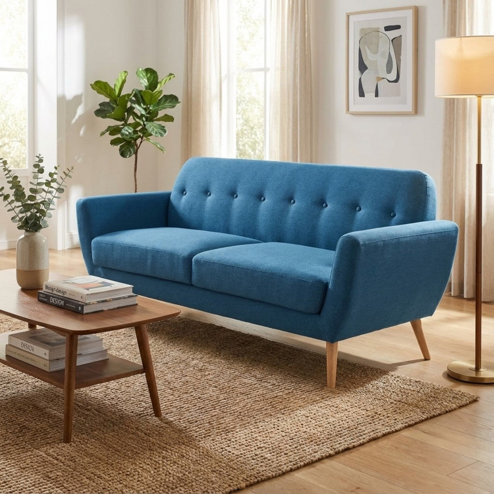 Divano Burton blu inserito in un elegante salotto con tappeto in iuta, tavolino in noce e lampada da terra.