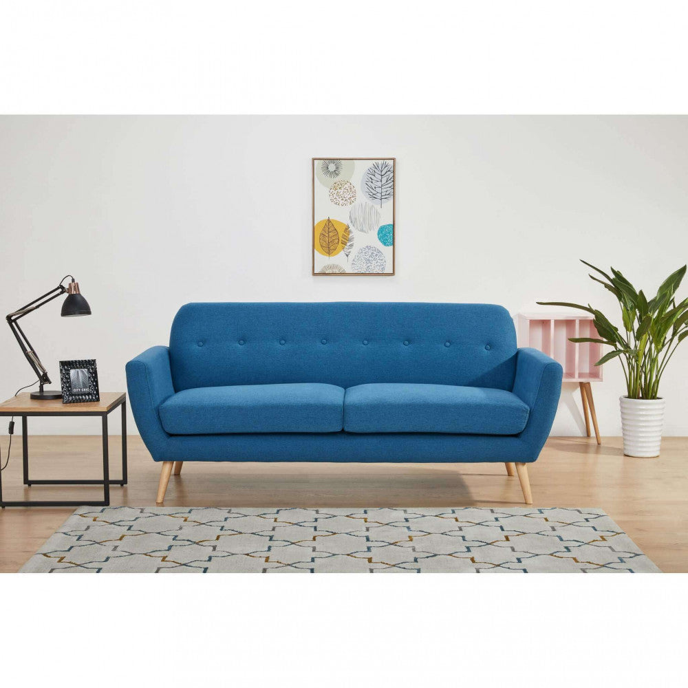 Inquadratura frontale del divano Burton in tessuto blu in un living contemporaneo con pavimentazione in legno chiaro.