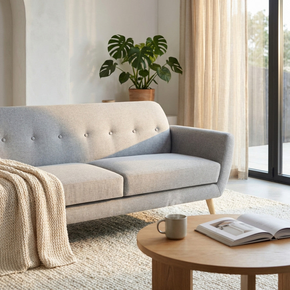 Divano 3 posti Burton in tessuto grigio chiaro ambientato in un living luminoso con tavolino in legno e pianta decorativa.