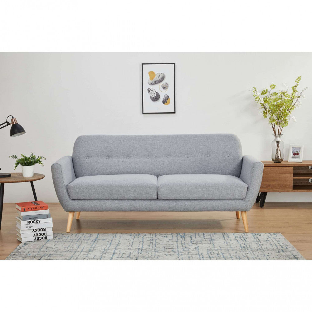 Divano 3 posti Burton inserito in un soggiorno dal design scandinavo con mobile in legno e libri decorativi.