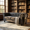 Divano 3 posti Chesterfield in velluto grigio taupe, ambientato in una lussuosa biblioteca classica con luce naturale.