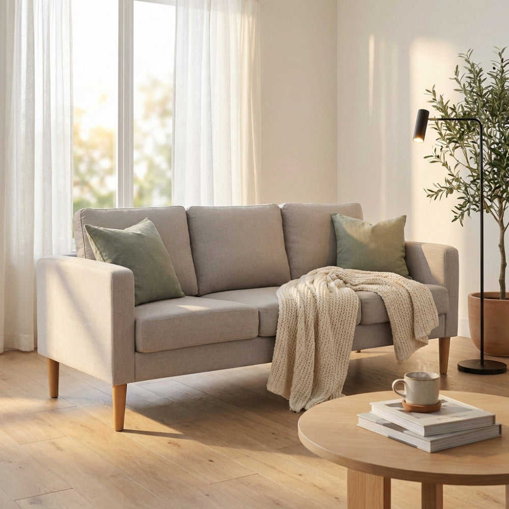 Divano 3 posti Ramsey in tessuto beige ambientato in un luminoso soggiorno con luce naturale e tavolino in legno.