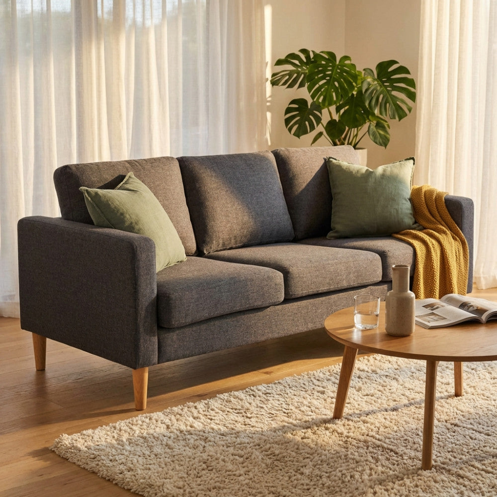 Divano 3 posti Ramsey in tessuto grigio scuro ambientato in un luminoso soggiorno dal design nordico.