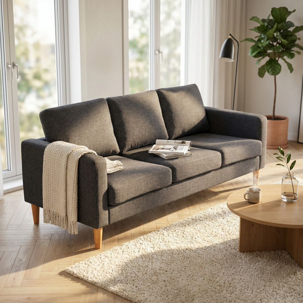 Vista angolare del divano Ramsey grigio scuro con plaid decorativo in un living contemporaneo.