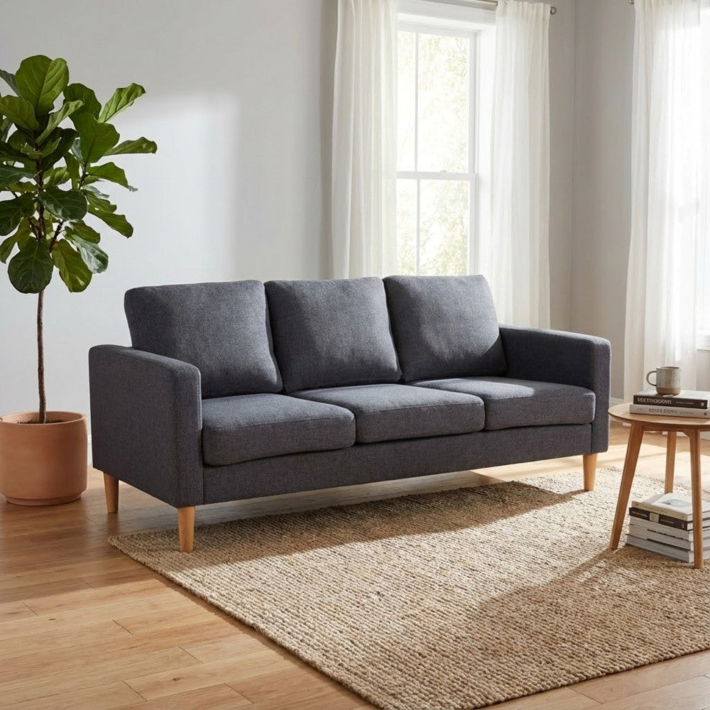Divano Ramsey inserito in un ambiente domestico elegante con tappeto in juta e pianta ornamentale.
