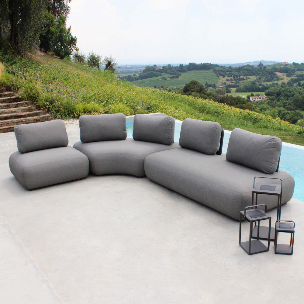 Set completo del divano angolare Malawi inserito in un rigoglioso giardino panoramico.