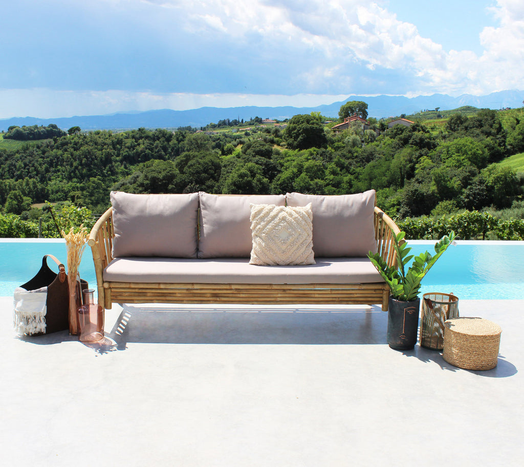 Divano BRONX in legno marrone a bordo piscina con cuscini decorativi e vista panoramica.