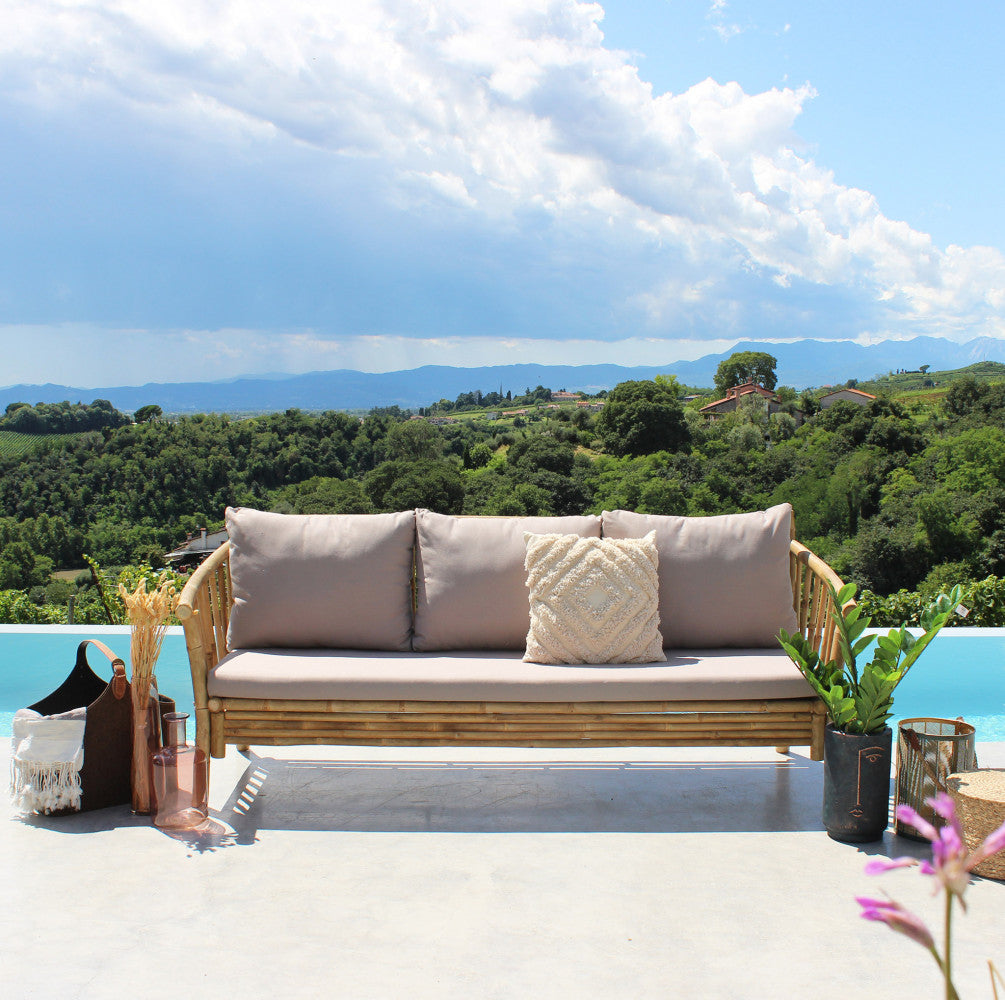 Vista frontale del divano BRONX a bordo piscina, circondato da vasi eleganti e natura.