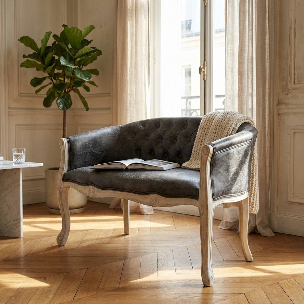 Divano Coleman a due posti in ecopelle grigio scuro ambientato in un luminoso salotto parigino con pianta decorativa.