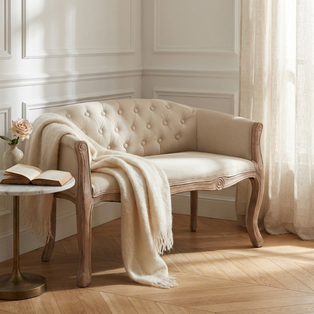 Divano a due posti Coleman in tessuto beige ambientato in un salotto classico con coperta in lana.