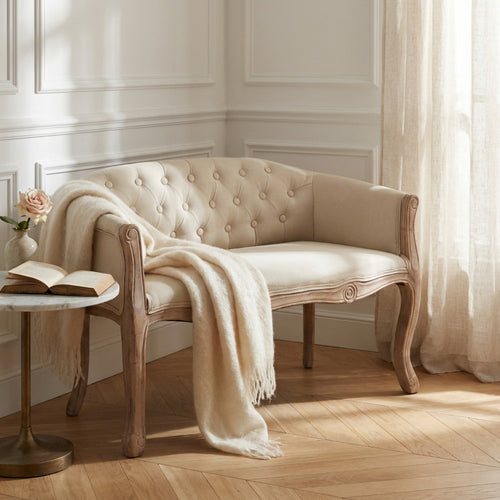 Divano a due posti Coleman in tessuto beige ambientato in un salotto classico con coperta in lana.
