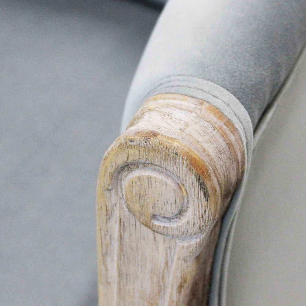 Dettaglio ravvicinato del bracciolo in legno sbiancato, che rivela le venature naturali e l'intaglio a spirale artigianale.