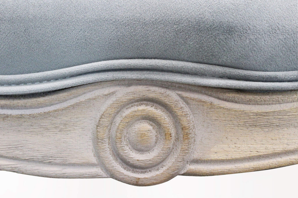 Particolare della seduta in velluto grigio e della cornice inferiore in legno con motivo circolare intagliato a mano.