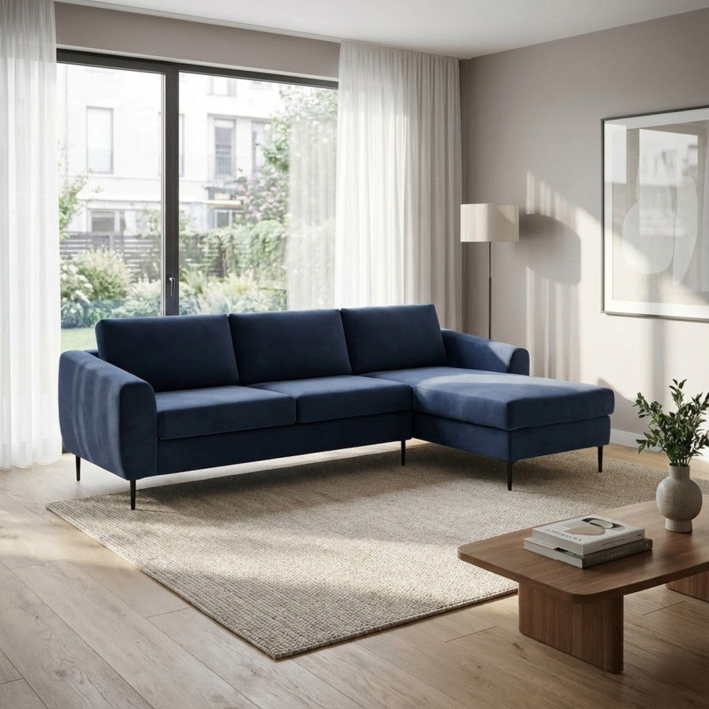 Divano a 4 posti Gregory in tessuto blu ambientato in un living con ampie vetrate.