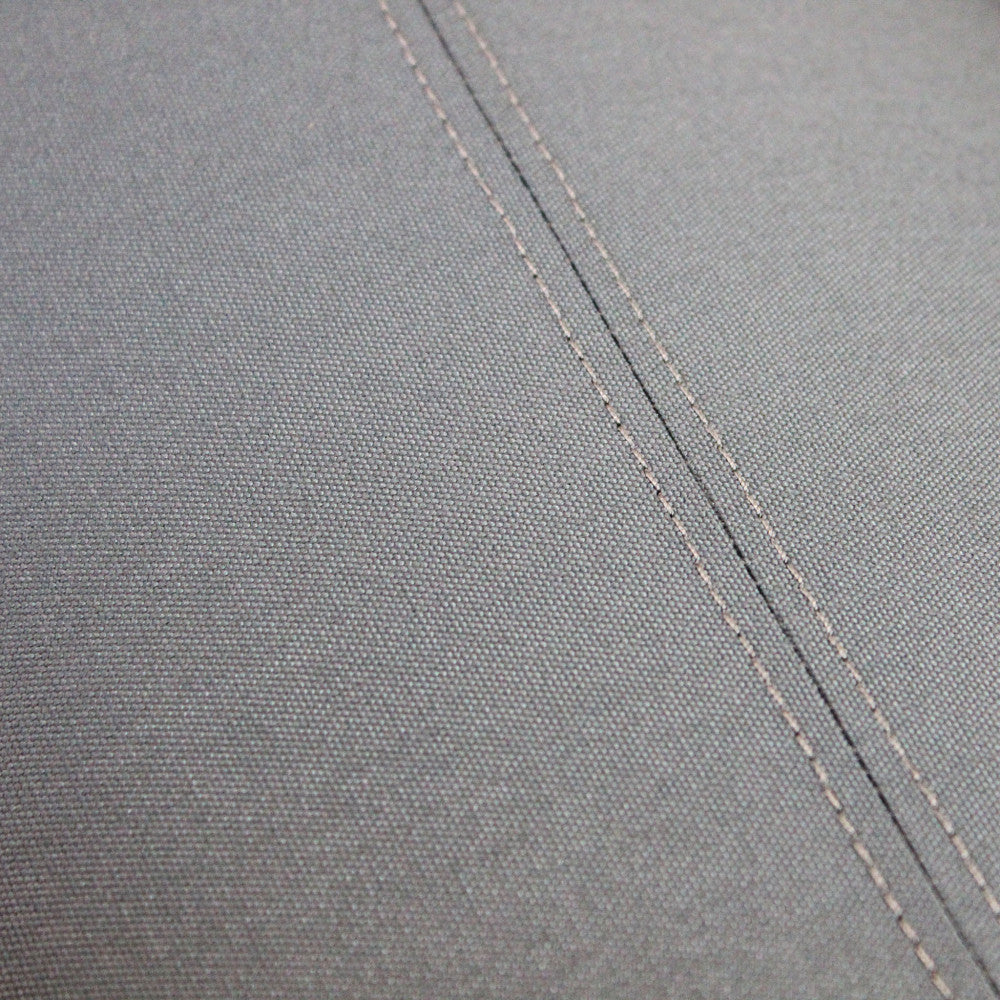 Dettaglio ravvicinato delle cuciture sartoriali e della trama del rivestimento grigio scuro del divano Tucumã.